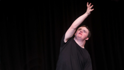 Euan Evans wearing a plain black t-shirt with one arm raised in the air