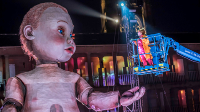 A performer stood in a cherry picker raised up to the eye level of the giant model baby