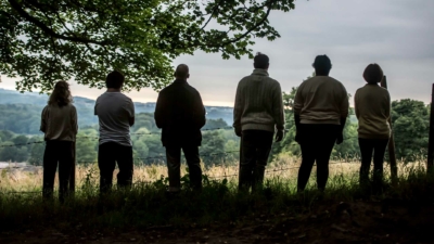 Six silhouetted people photographed from behind looking over a beautiful landscape